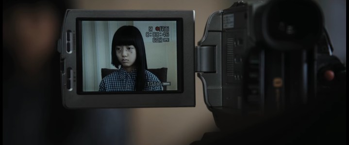 A little girl being filmed on a video camera in "Silenced" (2011).