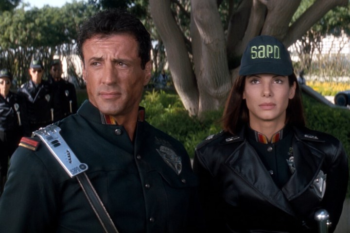 Sylvester Stallone stands next to Sandra Bullock in Demolition Man.