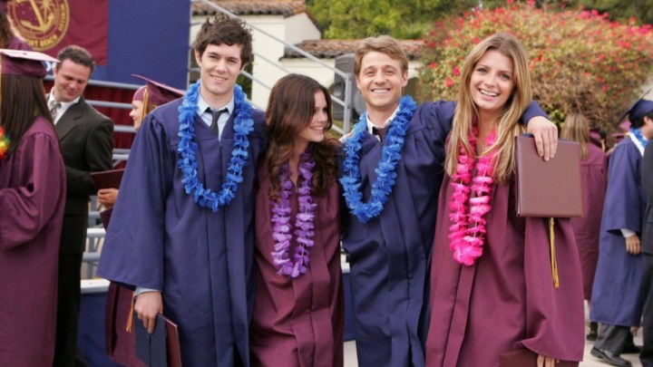 Four teenagers stand next to each other in graduation gowns in The O.C.