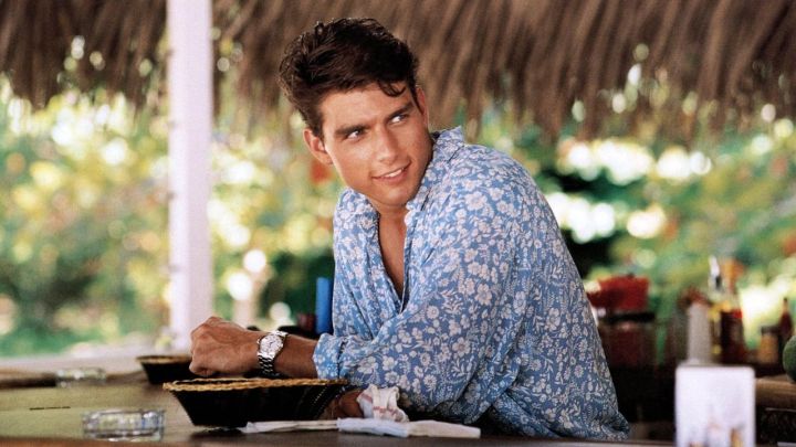 Tom Cruise as Brian Flanagan sitting at a beach bar in the film Cocktail.