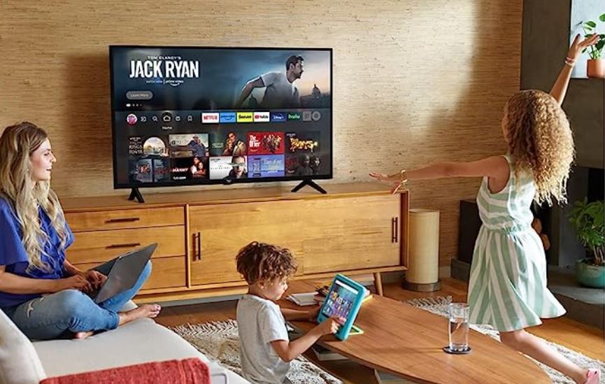 Uma família brinca em uma sala de estar com uma Amazon Fire TV na parede.