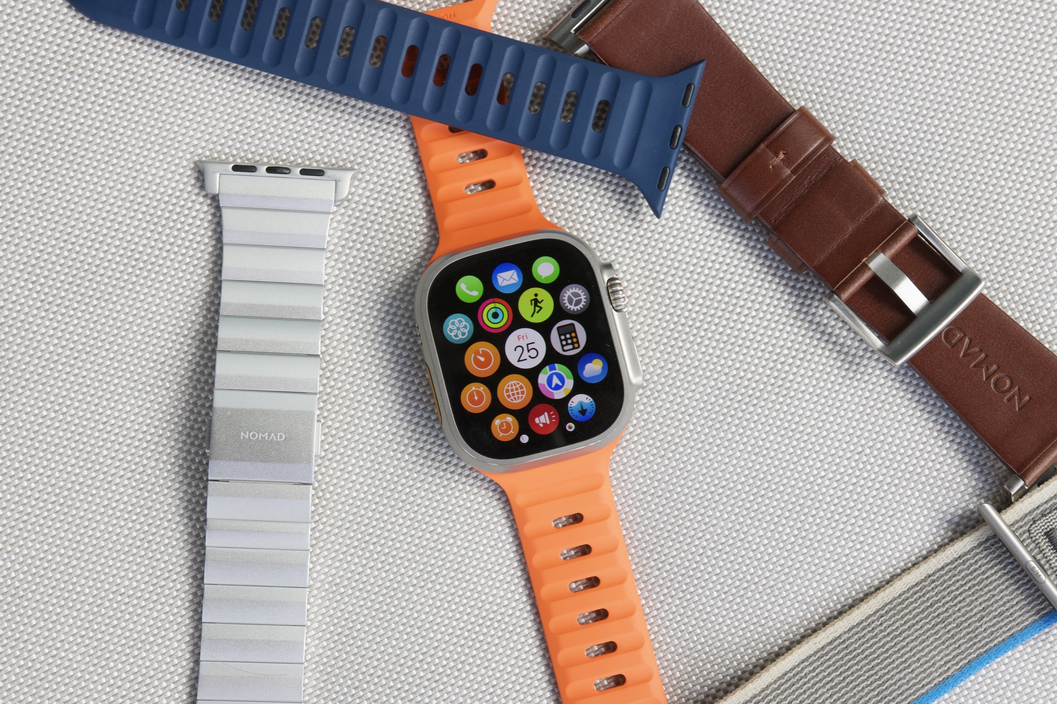 Apple Watch Ultra rodeado por várias pulseiras de relógio.