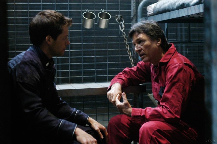 Lee Adama (Jamie Bamber) and Tom Zarek (Richard Hatch) converse in a cell in the Battlestar Galactica episode "Bastille Day"