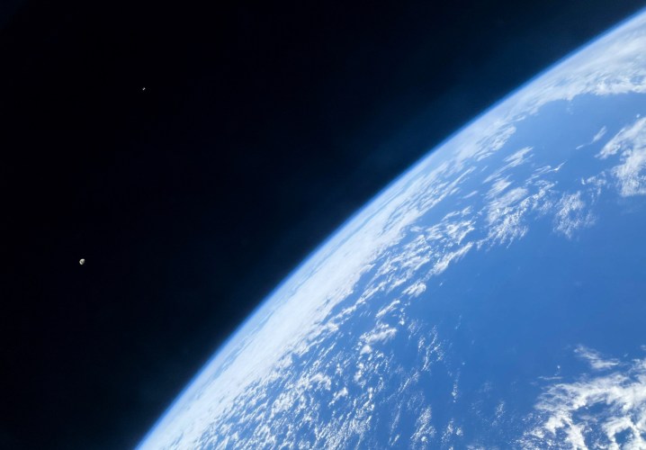 A photo taken from a SpaceX Crew Dragon showing Earth, the moon, and the space station.