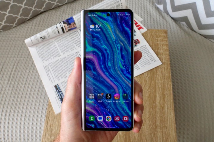 A person holding the Samsung Galaxy Z Fold 5, showing the cover screen.