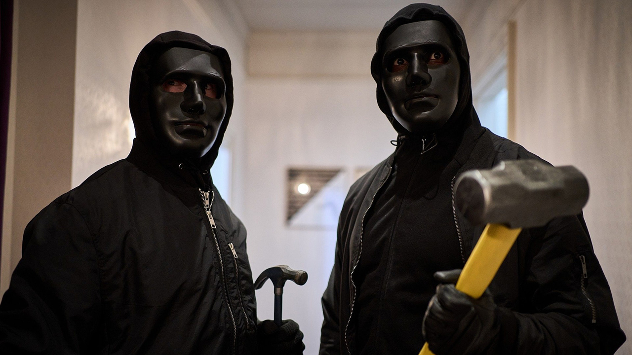 Two men wearing black hoodies and masked, one wielding a mallet and the other a hammer in a scene from Gangs of London.