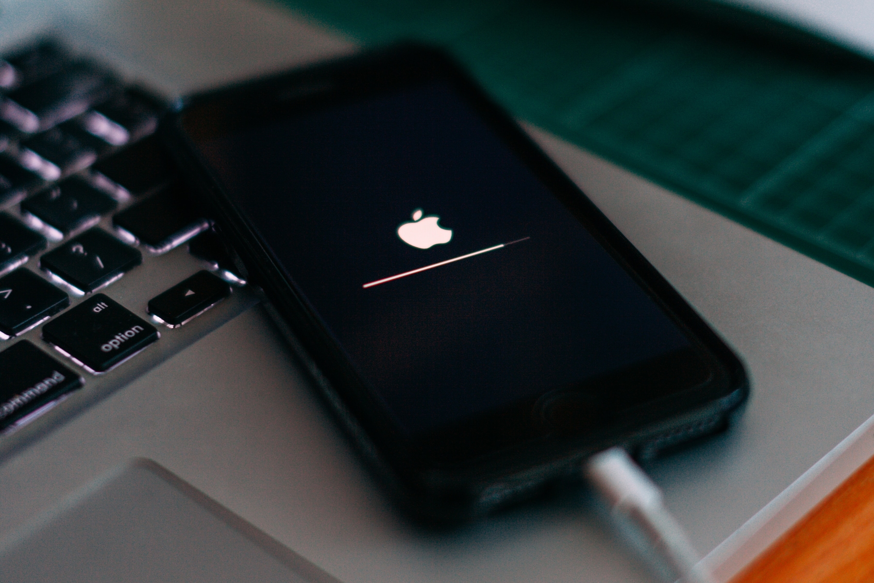 iPhone conectado encima de MacBook mostrando el logotipo de Apple durante una recuperación de actualización de software.