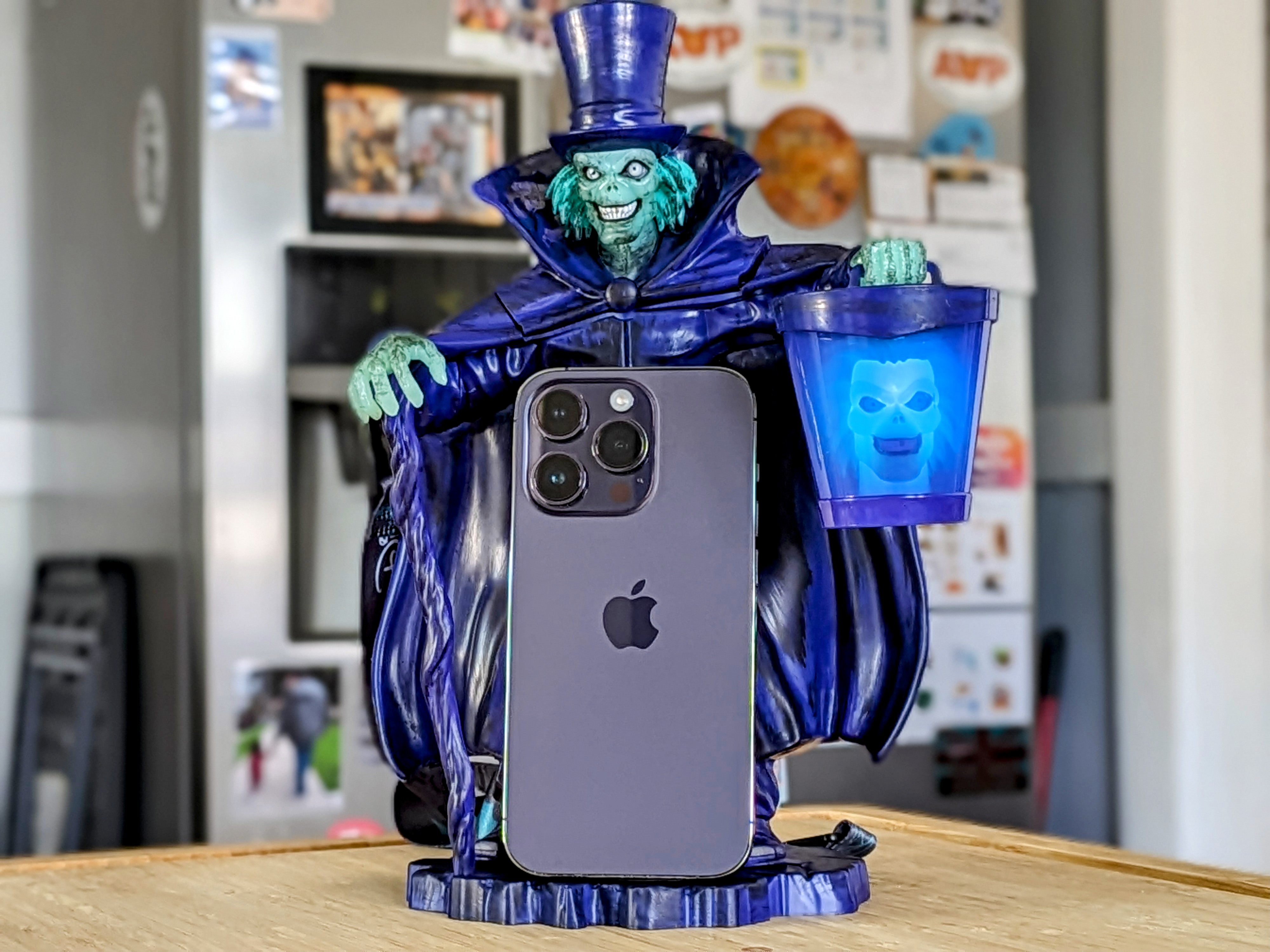 A Deep Purple iPhone 14 Pro resting on the base of a Hatbox Ghost sipper.