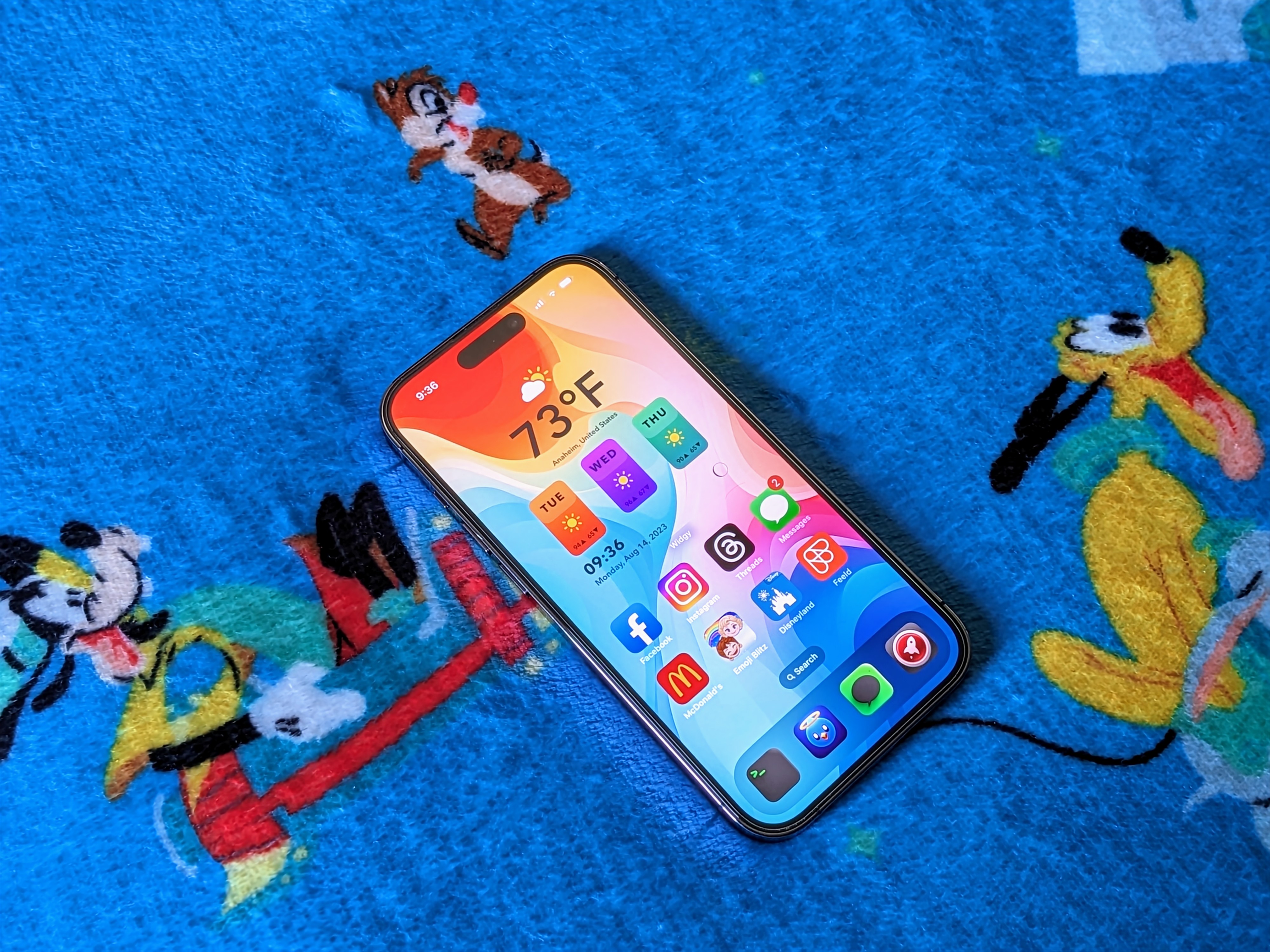 iPhone 14 Pro mostrando a tela inicial em um cobertor da Disneylândia.
