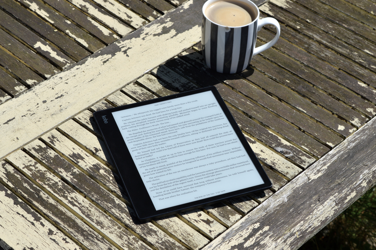 The Kobo Elipsa 2E laid outside on a table in the sun.