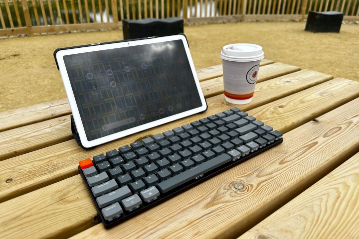 The Pixel Tablet with a Keychron K3 keyboard, on a bench.