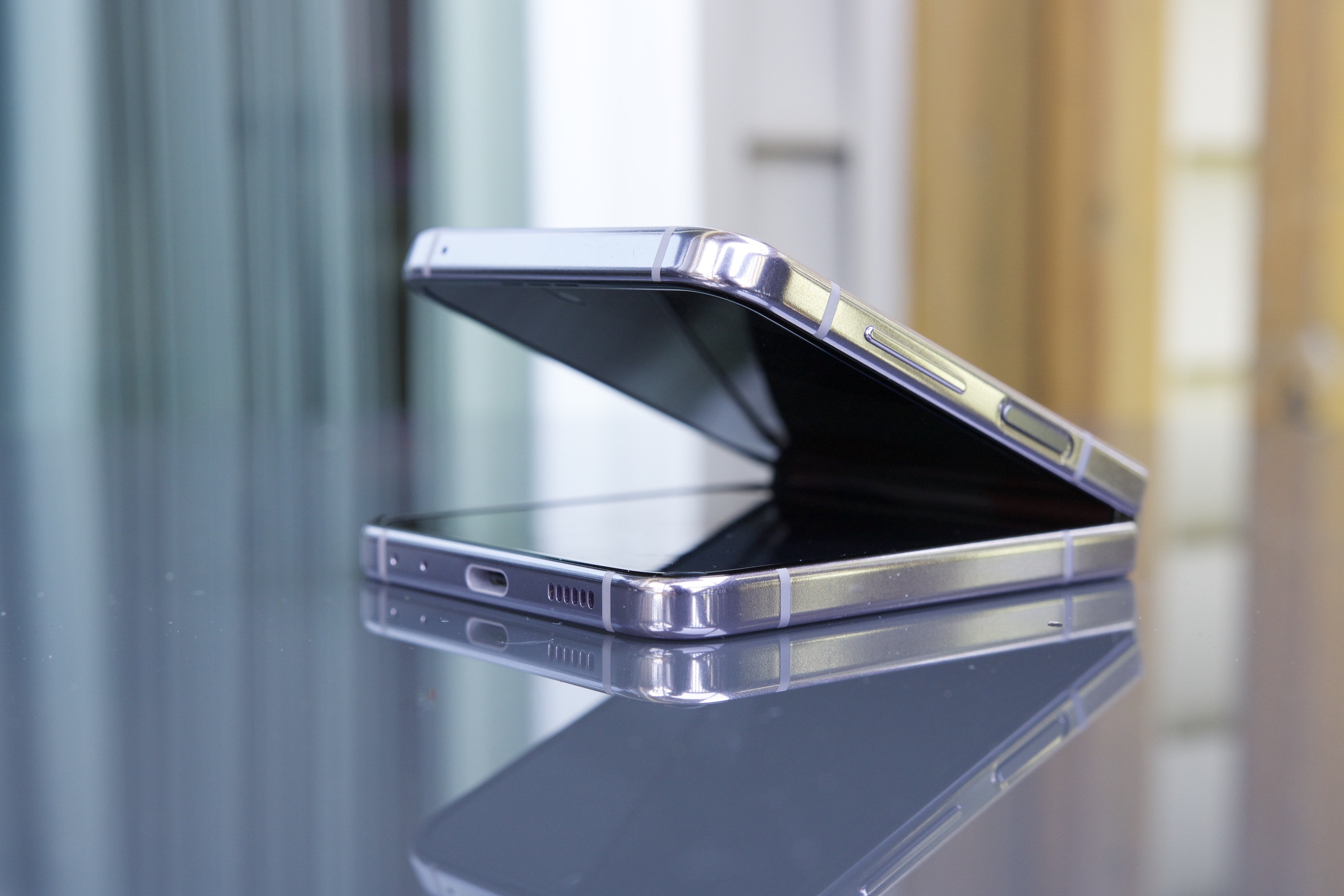 Samsung Galaxy Z Flip 5 نیمه باز، روی میز نشسته است.