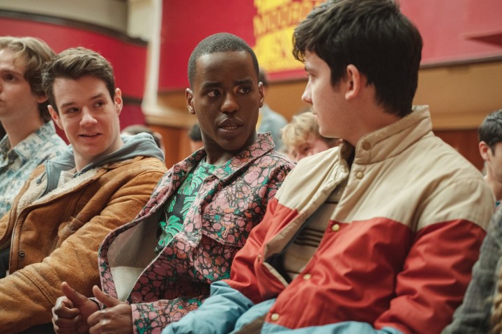 Three male students sit together in Sex Education season 4.