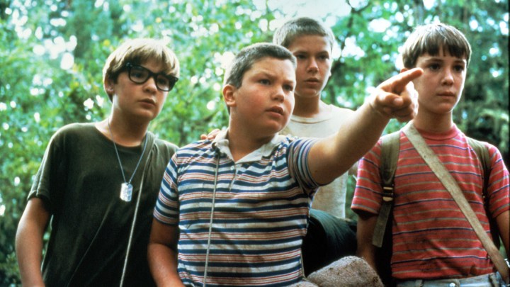 The four main kid characters from Stand by Me standing outside, one pointing at something.