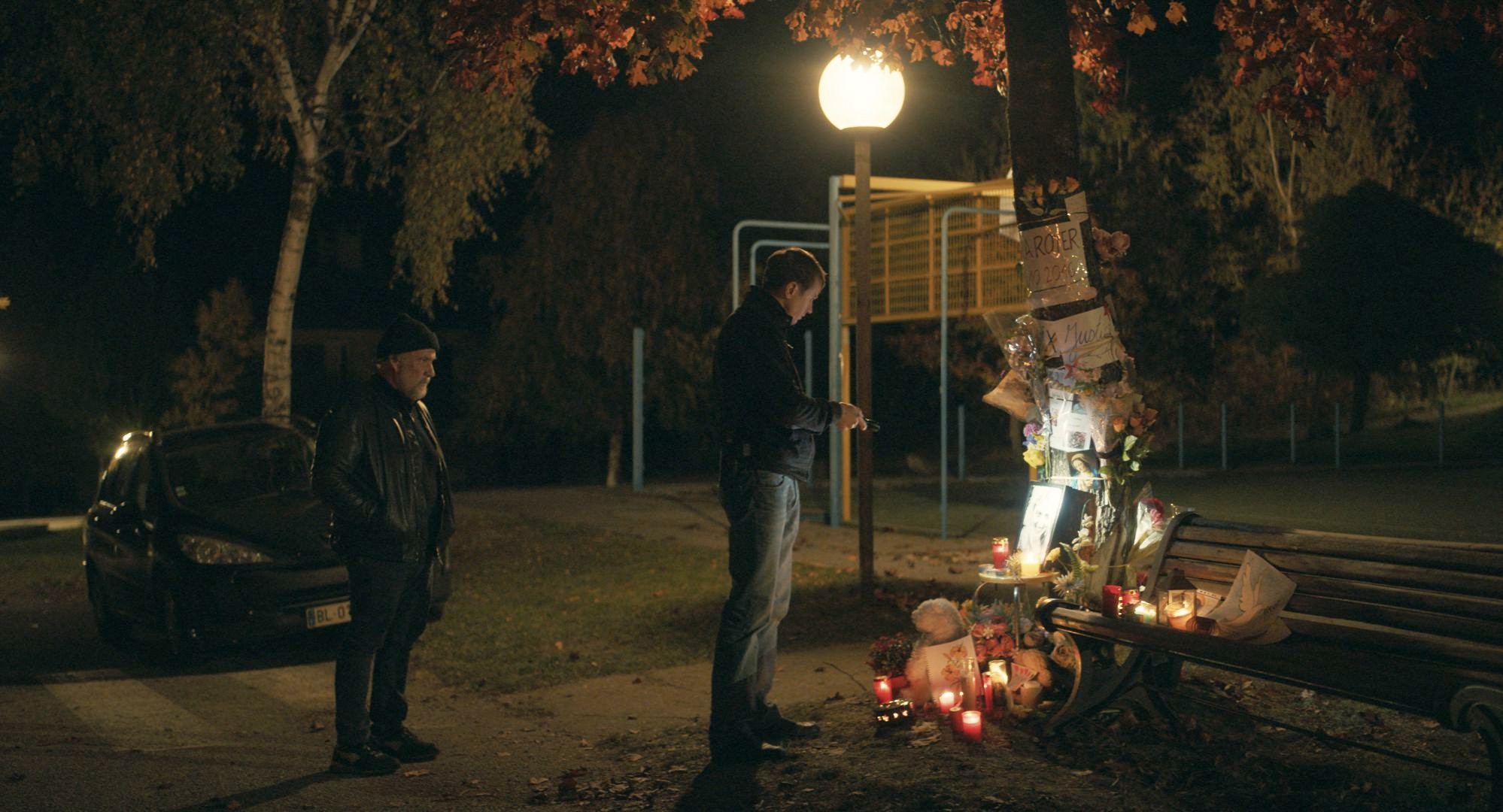 Dois homens visitam um memorial em The Night of the 12th.
