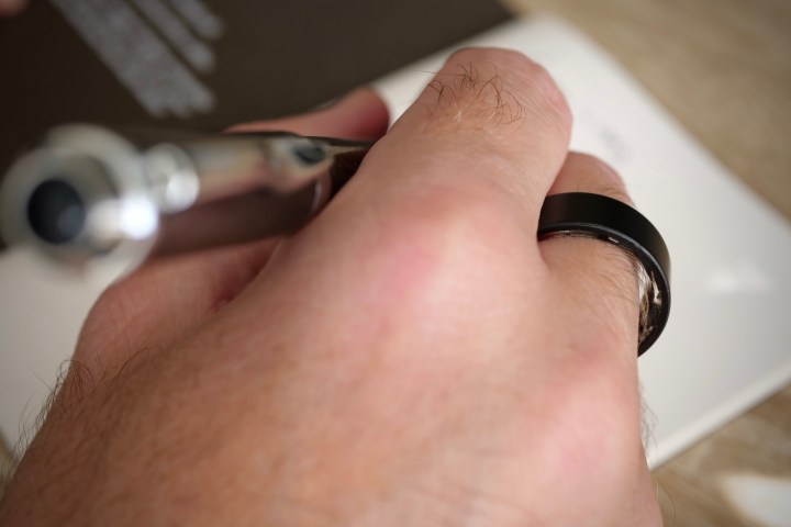 A person wearing the Ultrahuman Air ring, and writing.
