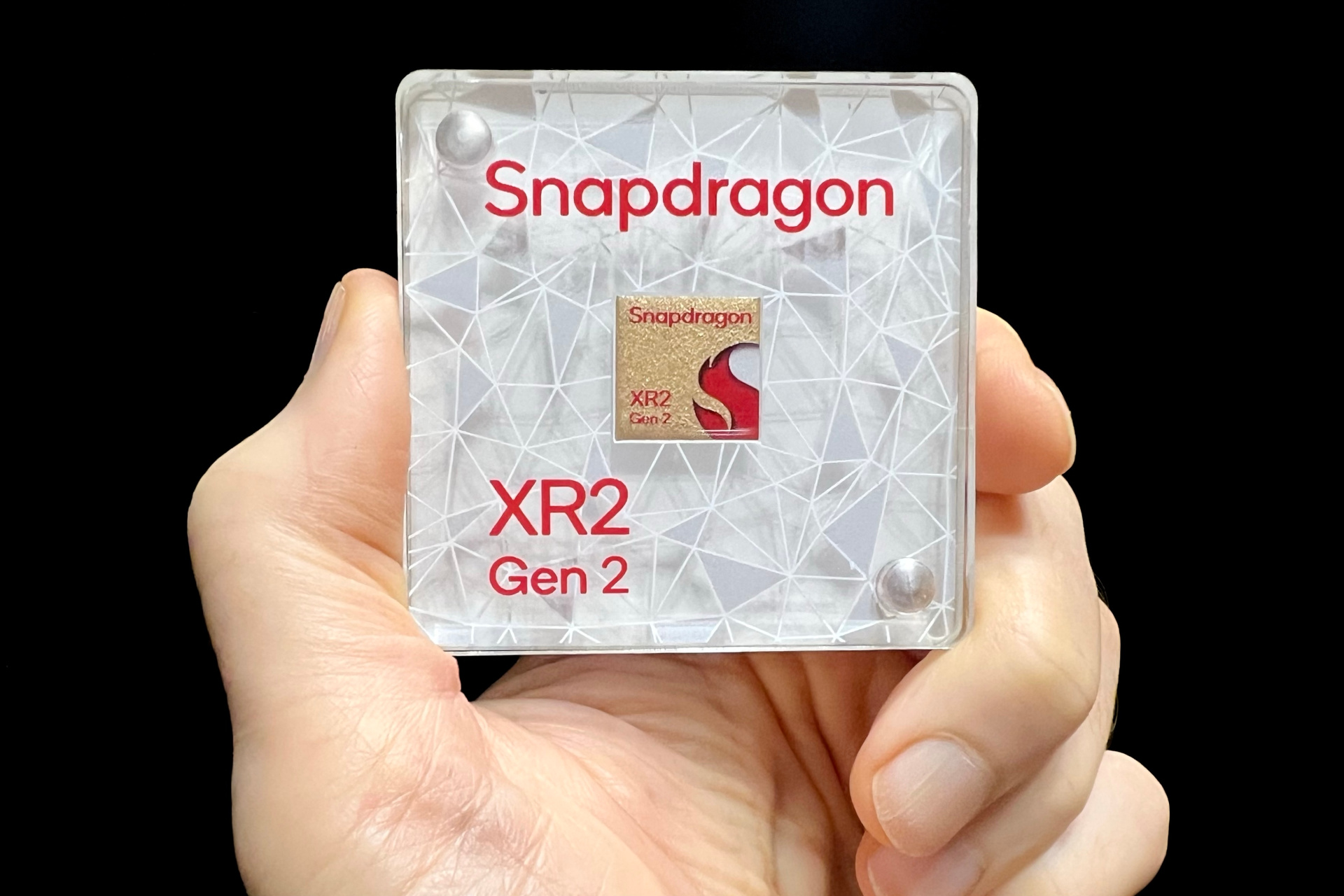Alan Truly tiene in mano un modello da esposizione del chip Snapdragon XR2 Gen 2 di Qualcomm.