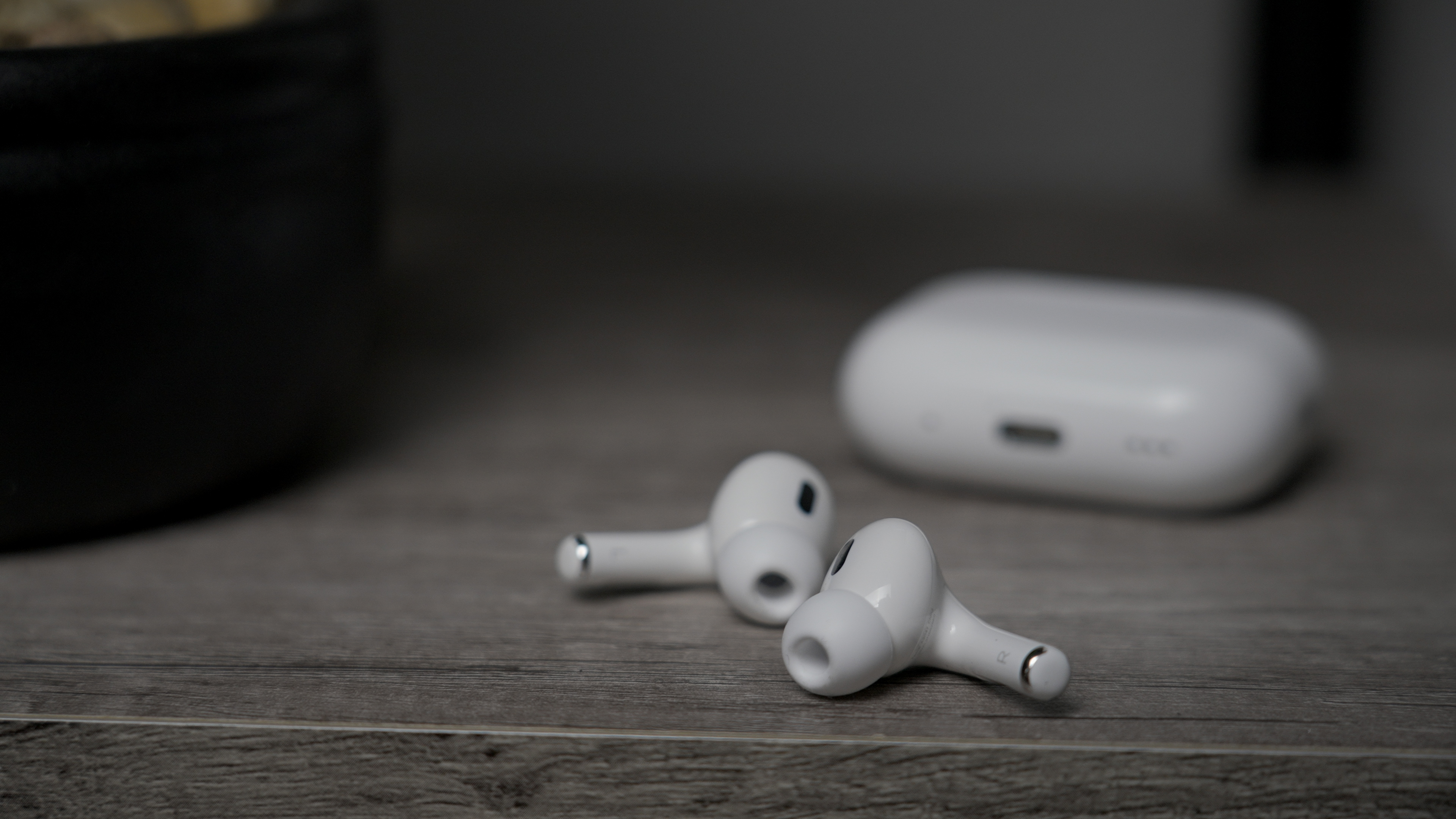 The Apple AirPods Pro 2 with USB-C and MagSafe buds on a table with case in the background.
