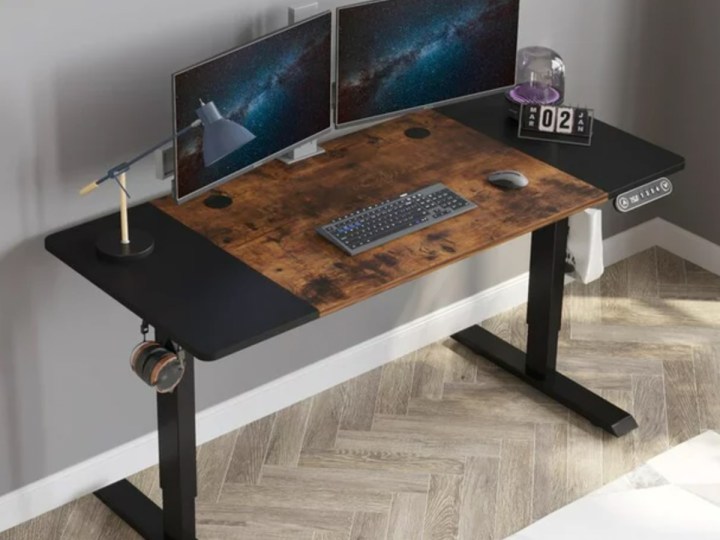 The Cometmin Electric Height Adjustable Standing Desk in an office.