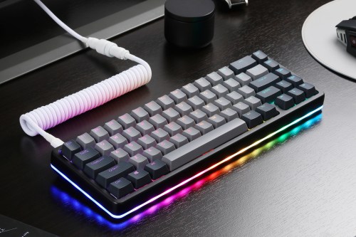 A Drop mechanical keyboard sits on a dark desk, lit up with RGB lights.