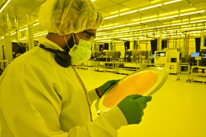 A worker holding an entire wafer that is stuck onto a mylar sheet.
