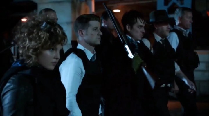 Selina, Jim, Cobblepot, and co. walking down a street in "Gotham."
