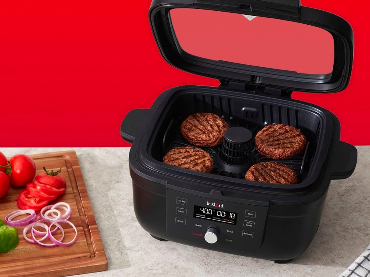 The Instant Pot 6-in-1 Smokeless Indoor Grill & Air Fryer on a counter cooking burgers.