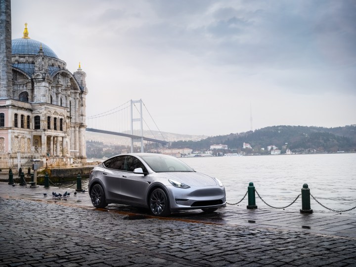 Une Tesla 3 est garée à côté d’un front de mer urbain.