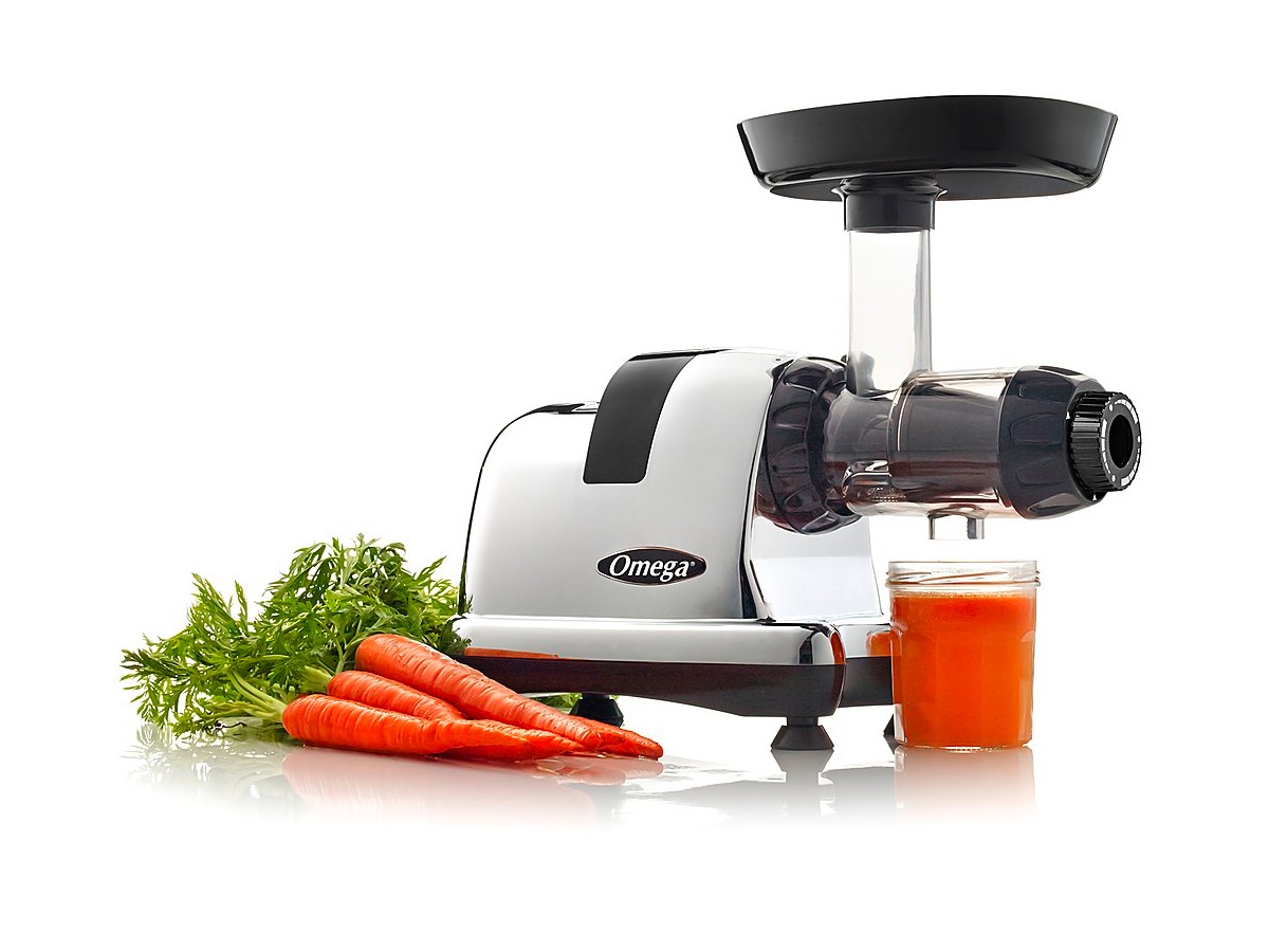 The Omega slow juicer and nutrition system with some carrots and juice against a white background.