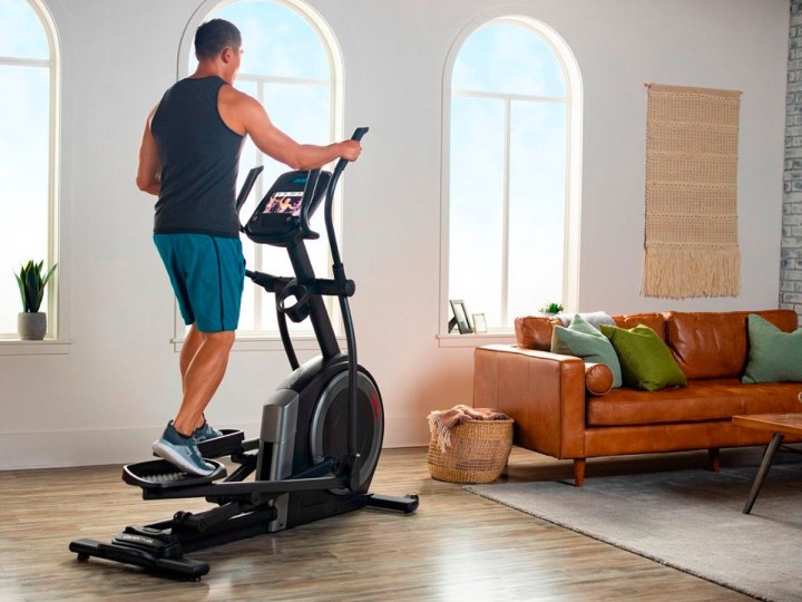A man working out with the ProForm Carbon EL elliptical machine in a nice apartment.