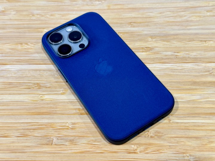 Coque Pacific Blue FineWoven sur un iPhone 15 Pro en titane naturel sur une table en bois.