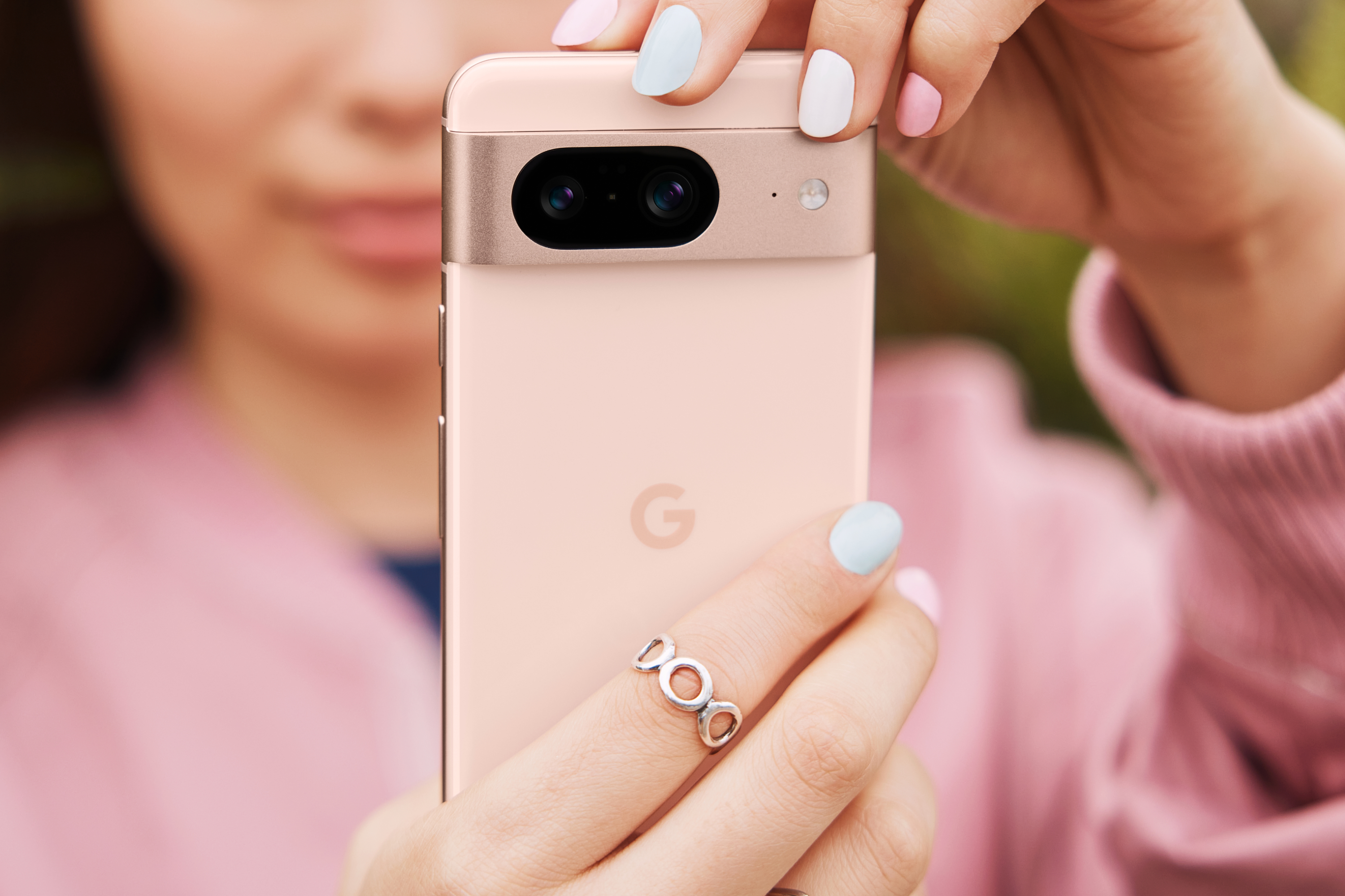 किसी ने गुलाबी Google Pixel 8 पकड़ रखा है, जबकि उसने गुलाबी शर्ट भी पहन रखी है।