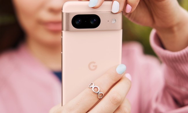 Someone holding up the pink Google Pixel 8, while also wearing a pink shirt.