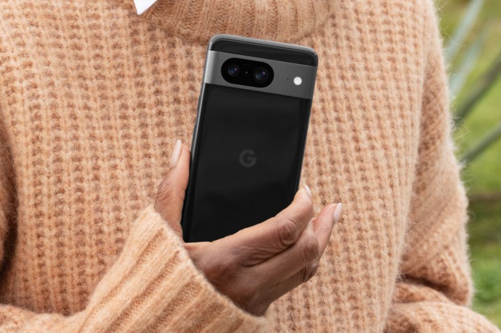 The black Google Pixel 8, being held by a person wearing a sweater.