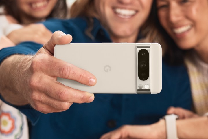 Someone holding a white Google Pixel 8 Pro to take a group selfie.