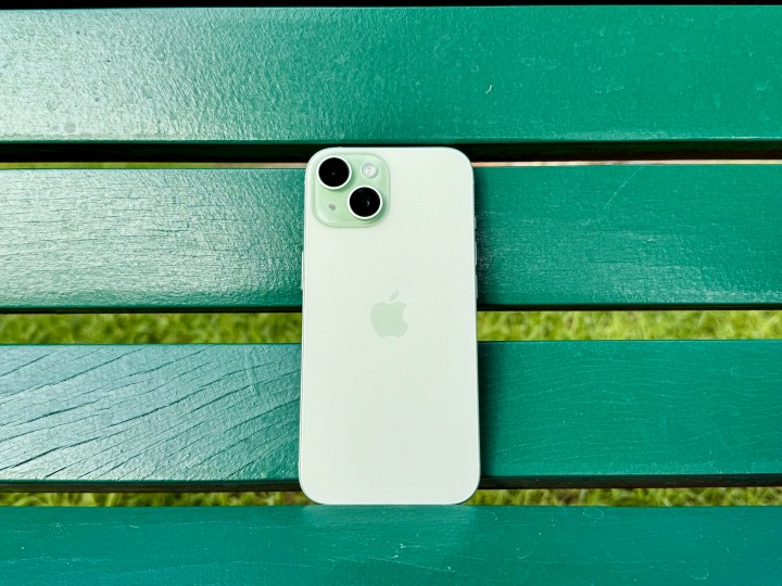 Un iPhone 15 verde su una panchina verde.