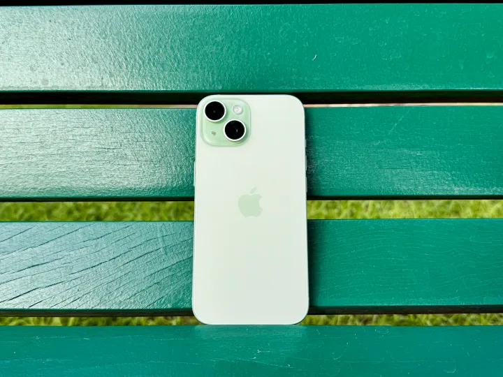 Un iPhone 15 verde sobre un banco verde.