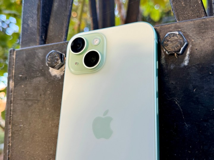 Un iPhone 15 vert montrant l’appareil photo et le dos en verre mat.