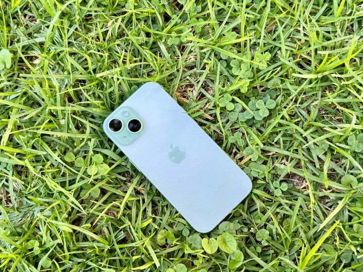 A green iPhone 15 in grass.