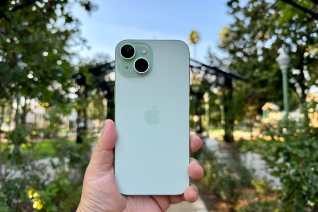Holding a green iPhone 15 in a rose garden.