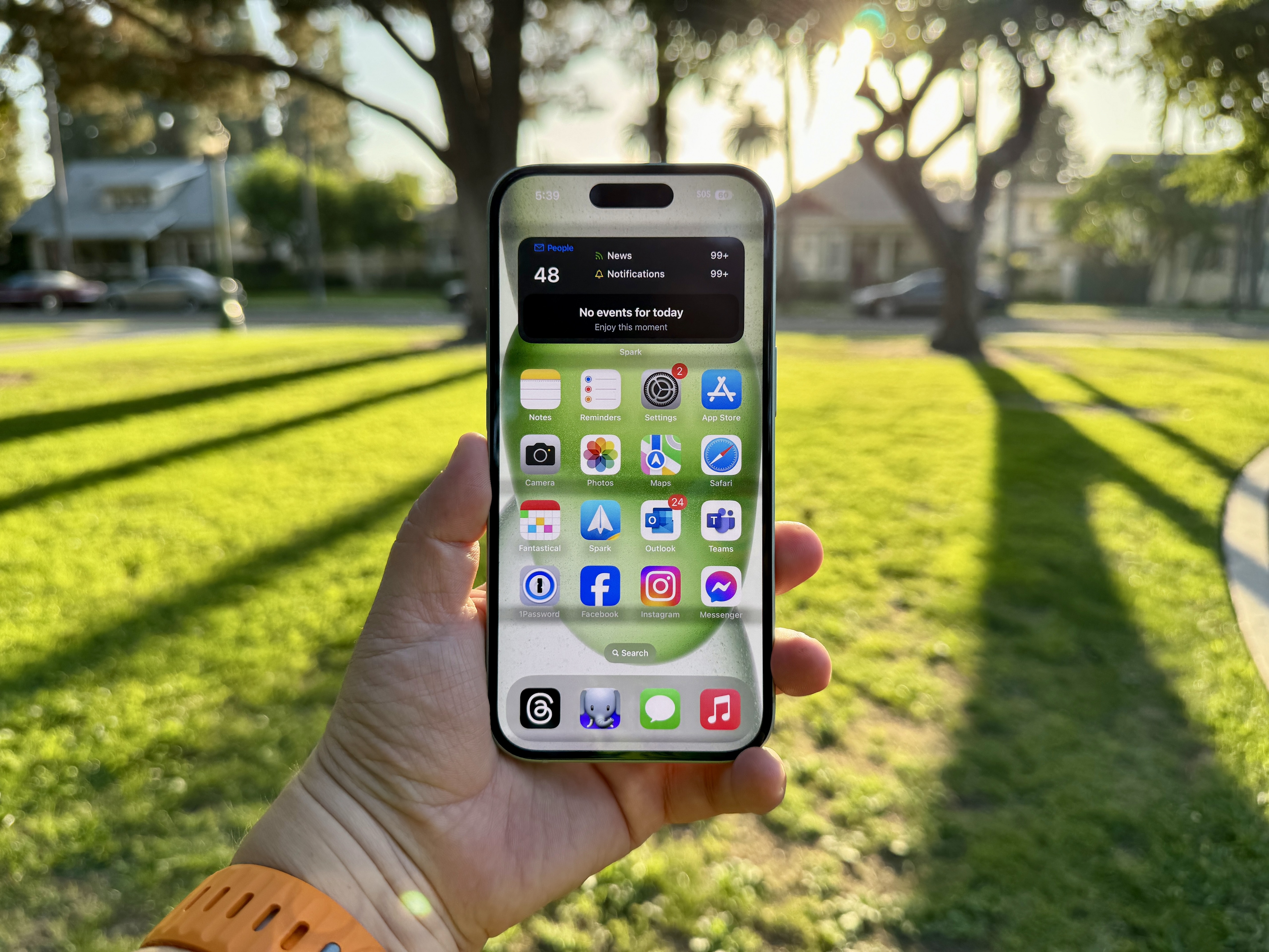 Ein grünes iPhone 15 in der Hand mit Startbildschirm.