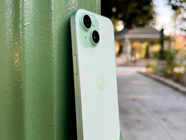 A green iPhone 15 leaning against a lamp post.