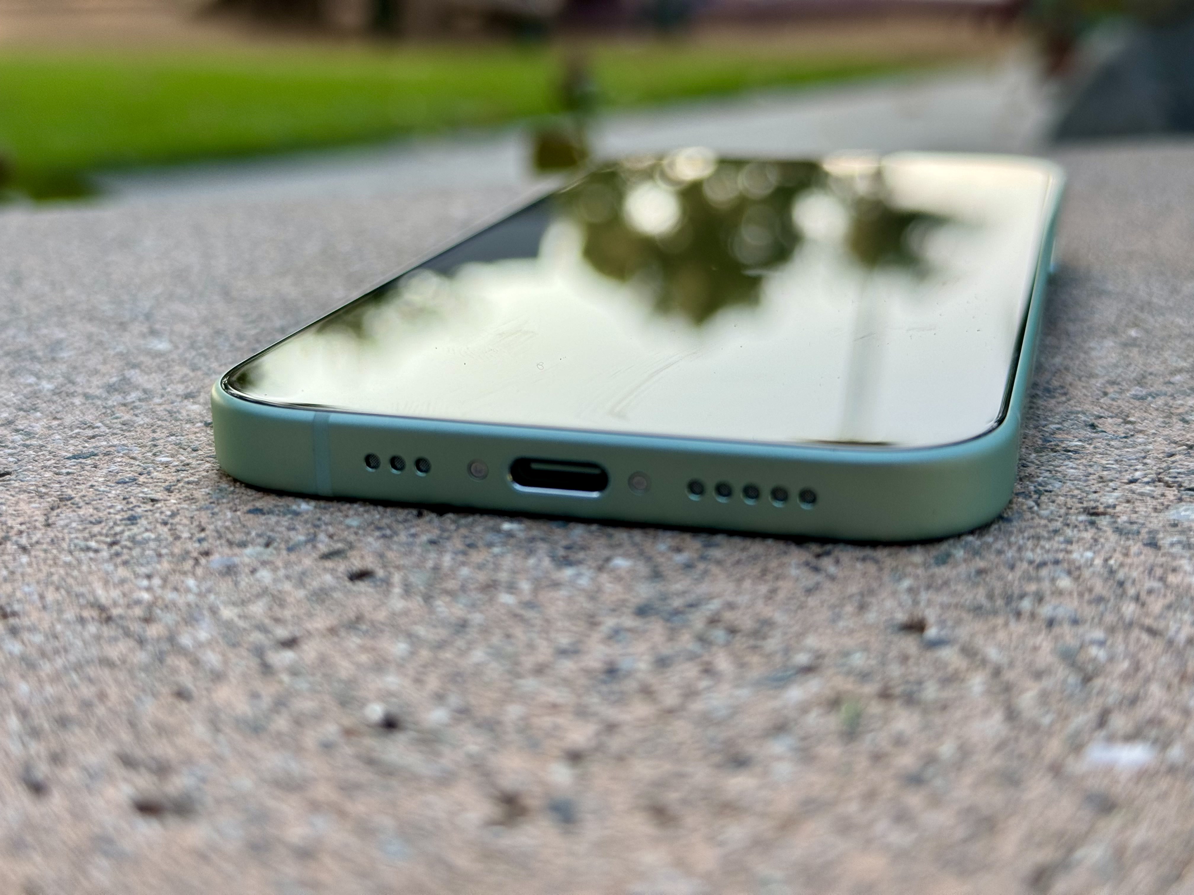 Вид на порт USB-C на зеленом фоне iPhone 15.
