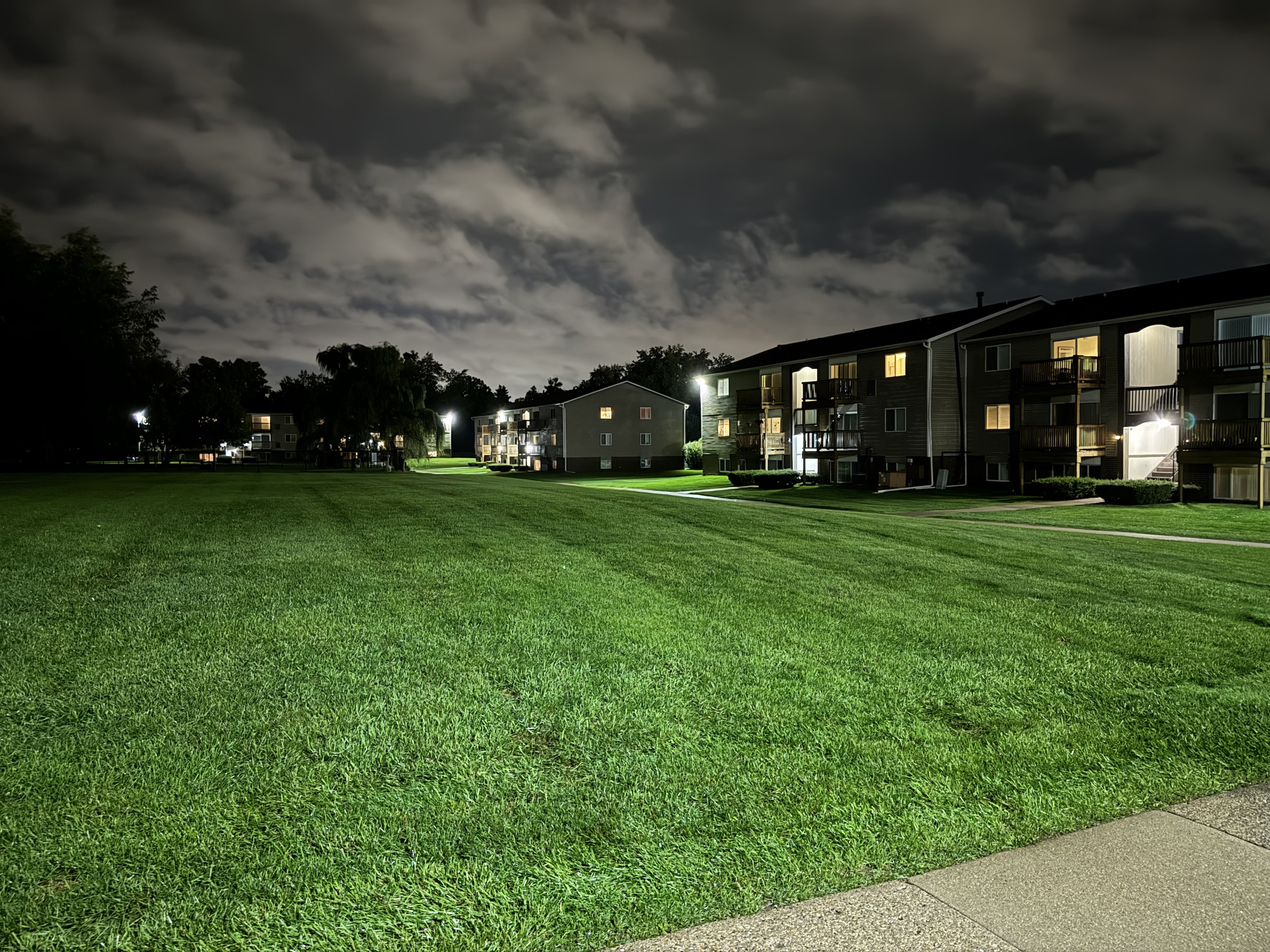 Photo from the iPhone 15 Pro Max main camera. It's a Night mode shot of an apartment complex.