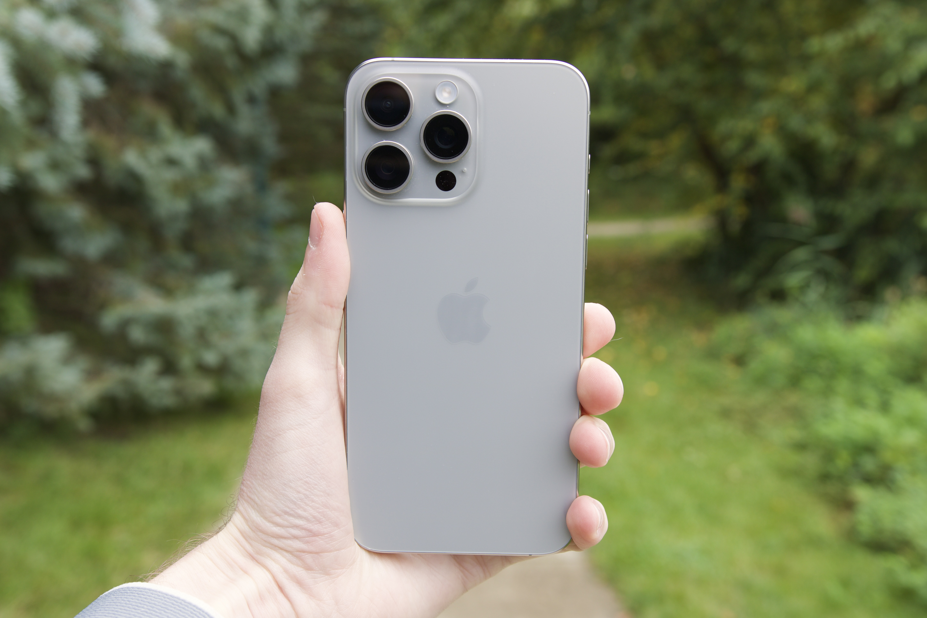 Someone holding the iPhone 15 Pro Max outside.