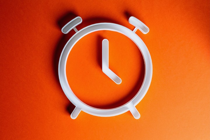 A clock being shown on an orange background.