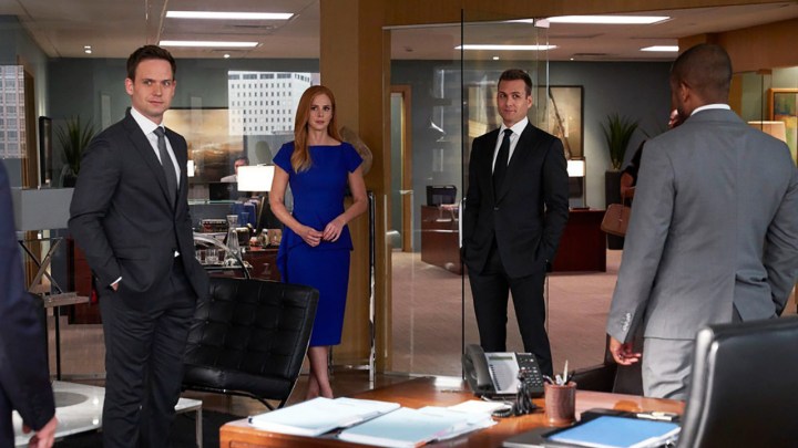 Mike, Donna, Harvey, and Alex standing in an office talking in a scene from Suits.