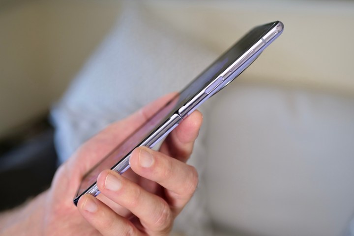 A person holding the Tecno Phantom V Flip, showing the side of the open phone.