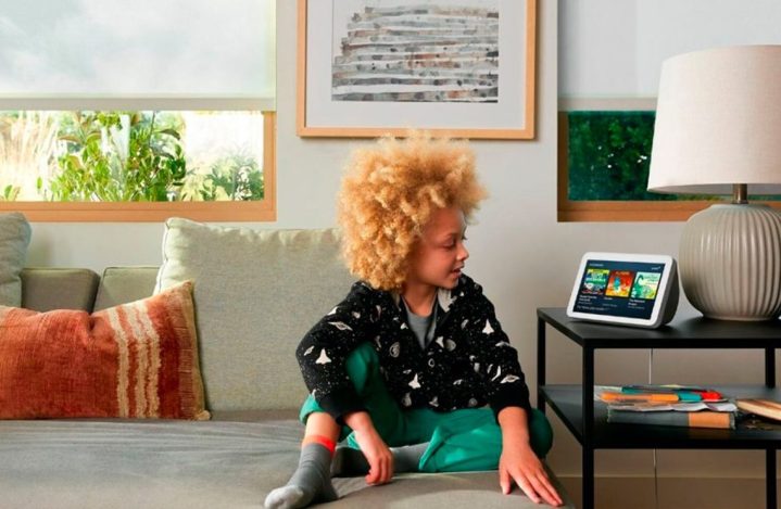 A kid sits on the couch and looks at the Amazon Echo Show (2nd Gen).