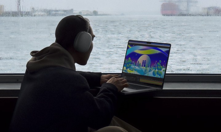 Someone using a MacBook Pro on a table in front of a scenic background.
